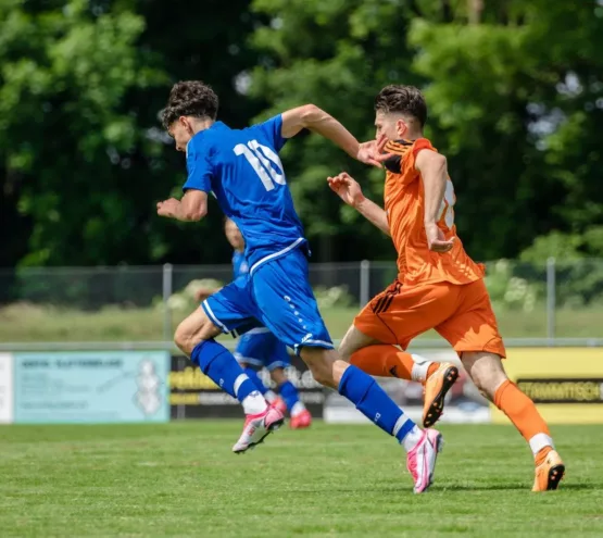 man in blue and orange jersey shirt running on green grass field during daytime