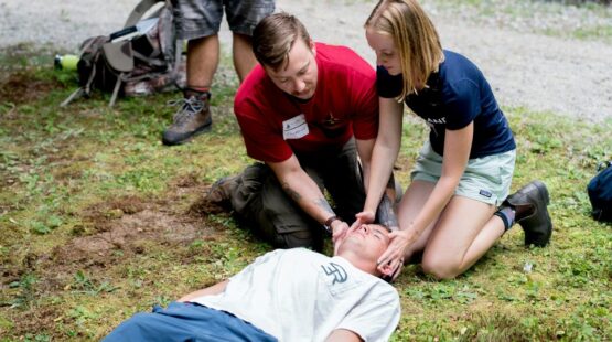Man teaching cpr on a dummy in outdoor setting